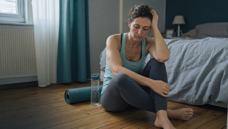 Femme d'une quarantaine d'années en tenue de sport, assise par terre après l'effort, l'air découragé : le sentiment que le corps ne répond pas malgré les efforts.